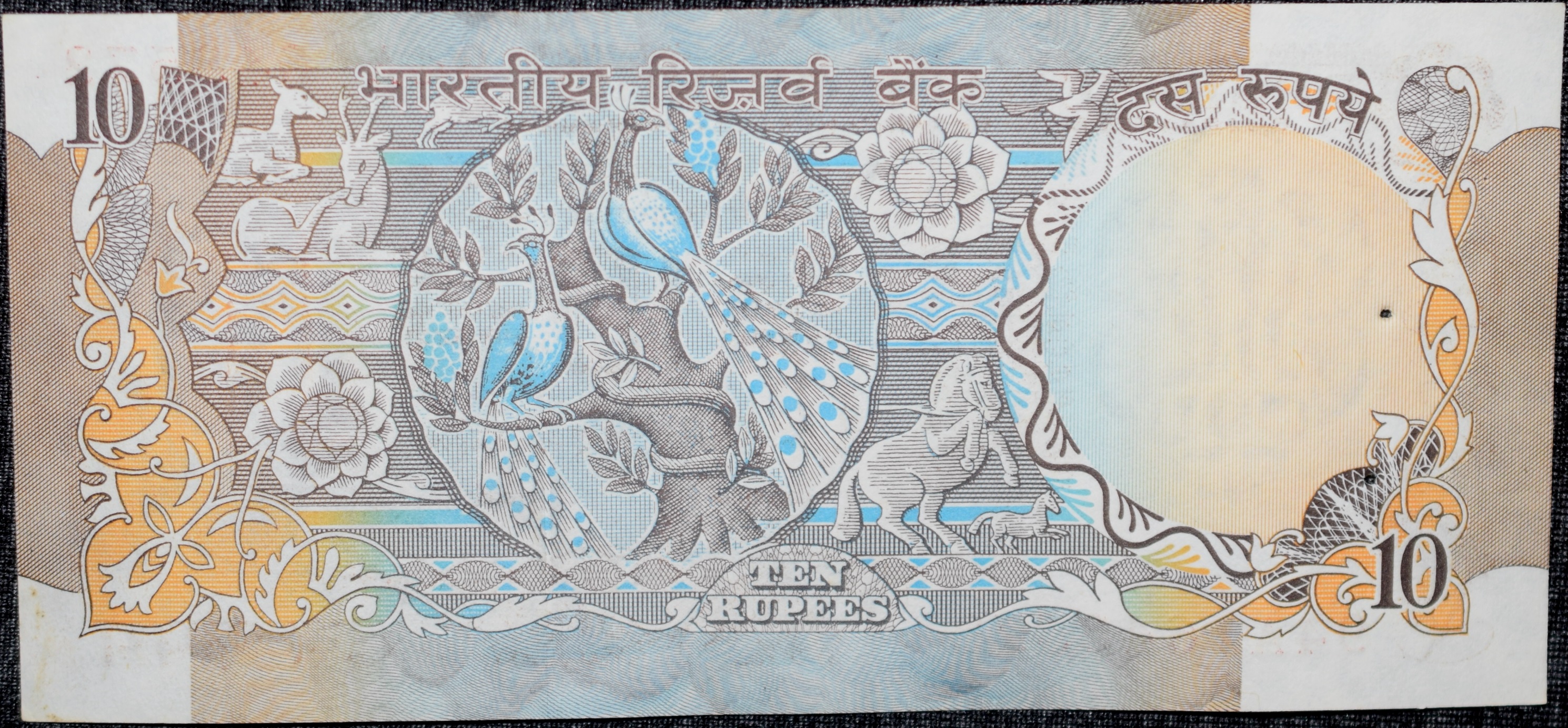 10 Rupees of Republic India (AD 1970-1990) with Two blue peacocks or Indian peafowl (Pavo cristatus) sitting on branches of an old mango tree surrounded by antelopes, horses, flowers, and a bird - R.N. Malhotra - Image 2